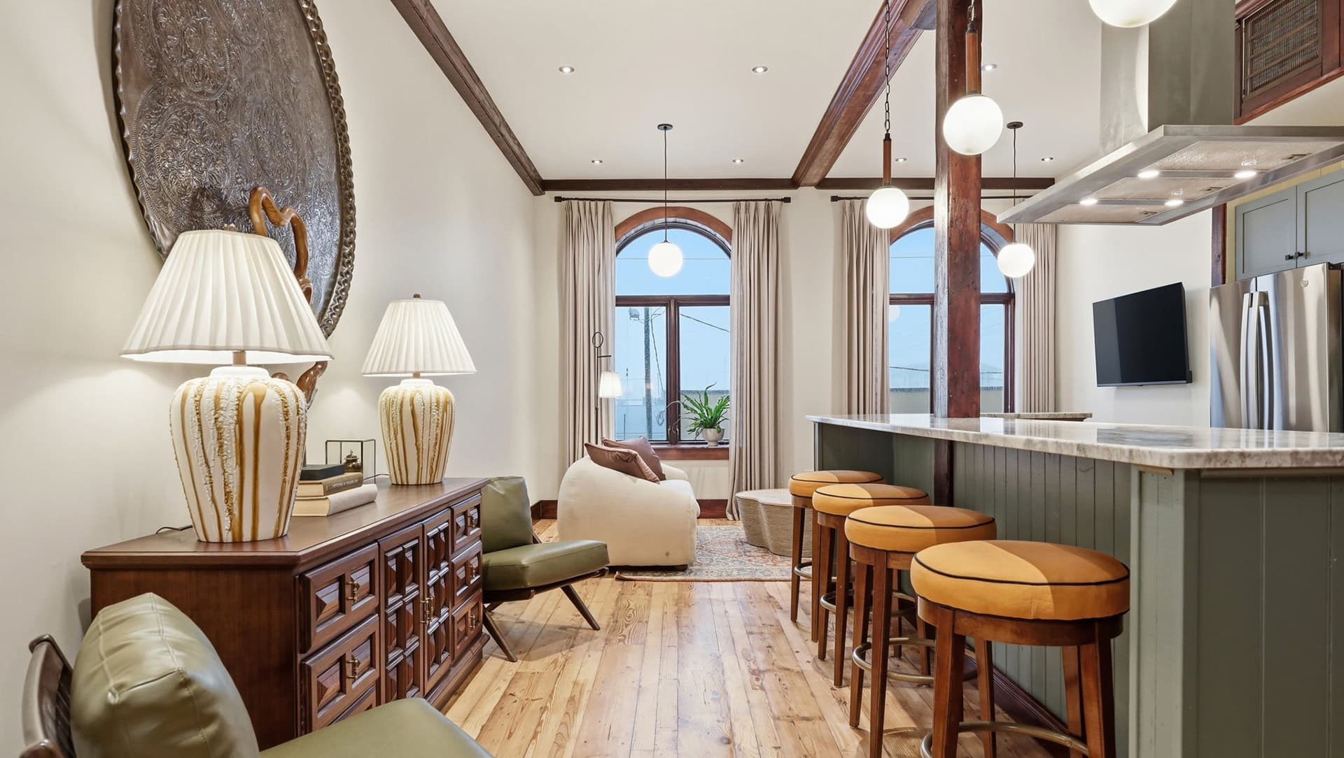 A stylish living space featuring modern furnishings, warm wood accents, and large windows.