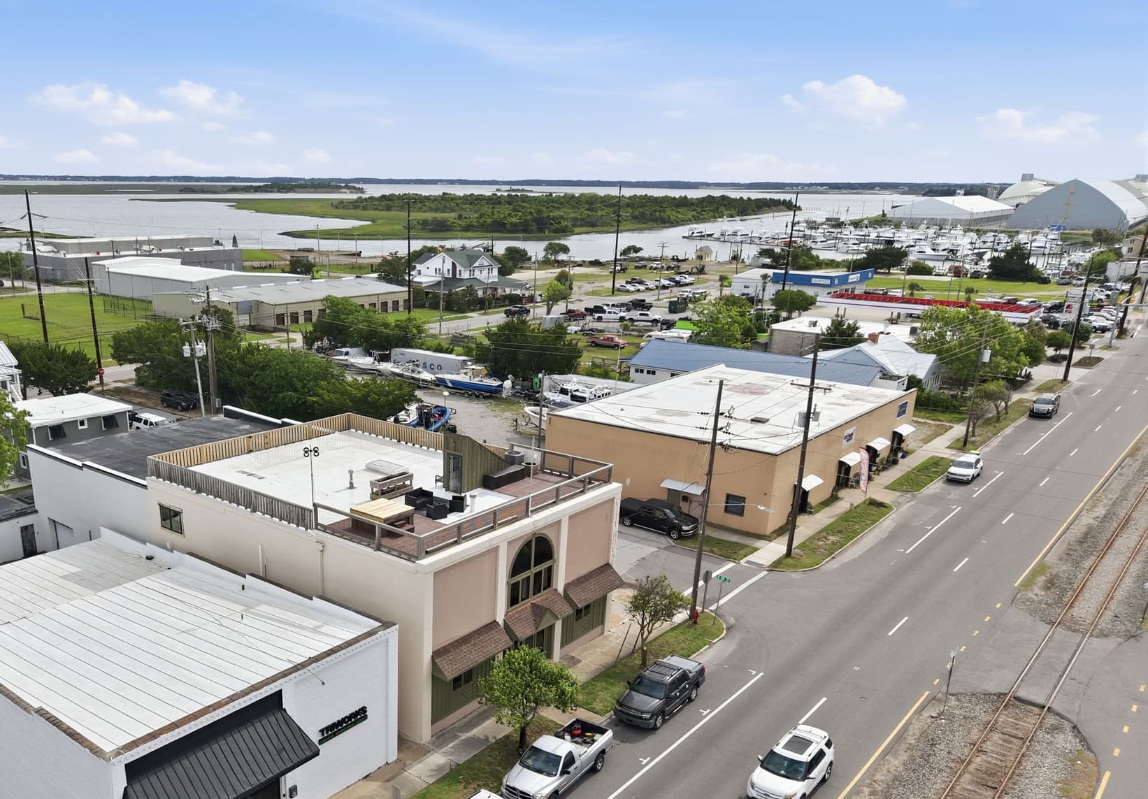 Aerial view of a coastal area featuring boats, buildings, and a road.